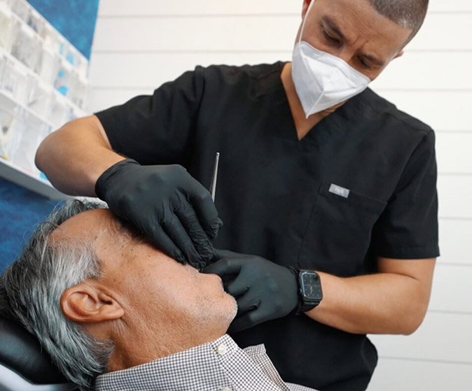 Dr. Gio and his assistant at Flossy Smiles reviewing a patient's dental x-rays with him